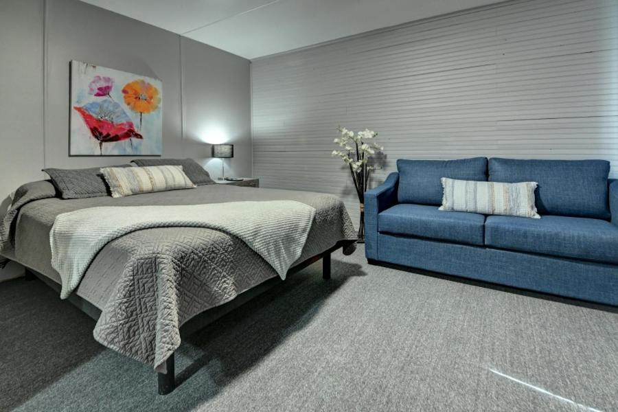 a bedroom with a bed and a blue couch at Motel Express in Saint-Antonin