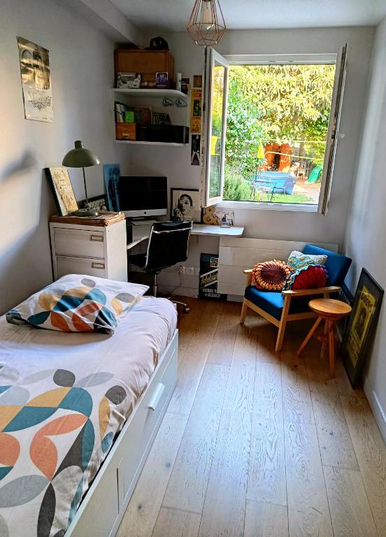 a bedroom with a bed and a desk and a window at Chambre et Salle de bain privées avec vue sur jardin dans maison familiale in Montreuil