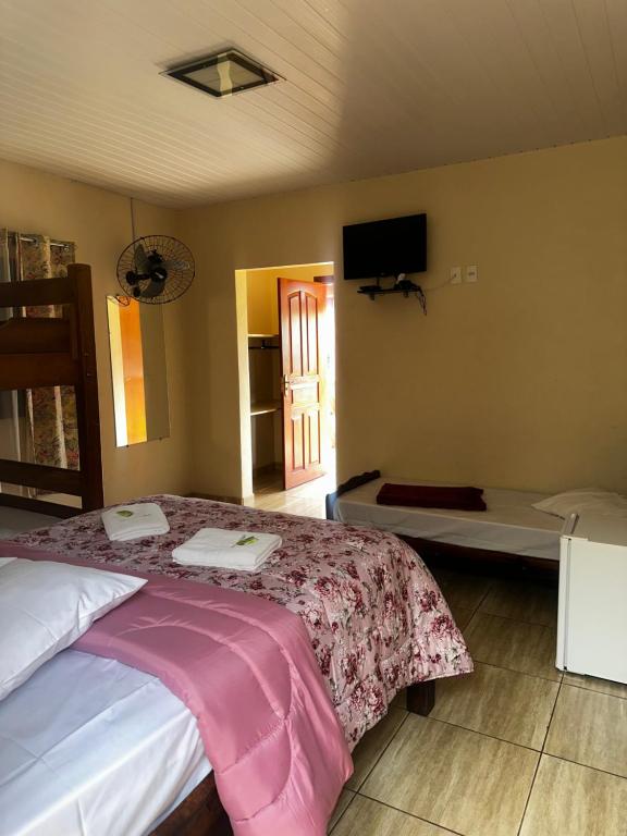 a bedroom with a bed and a tv on the wall at Pousada Natalino Broleze in Águas de Lindoia