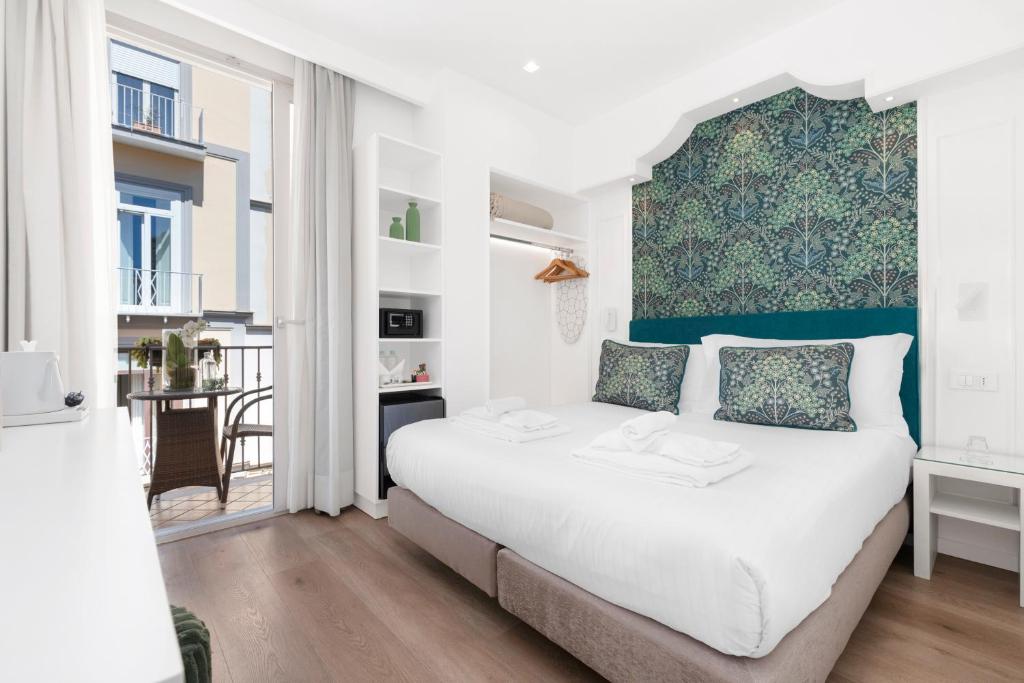a white bedroom with a large bed and a table at Hotel Sorrento City in Sorrento