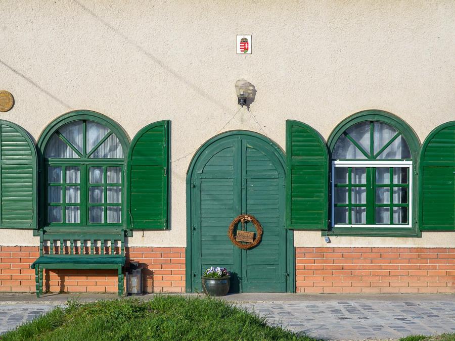 a building with green doors and a bench in front at Zöldspalettás in Monor