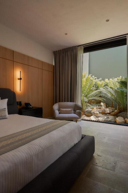 a bedroom with a bed and a chair and a large window at Casa Carmen Xólotl in Oaxaca City