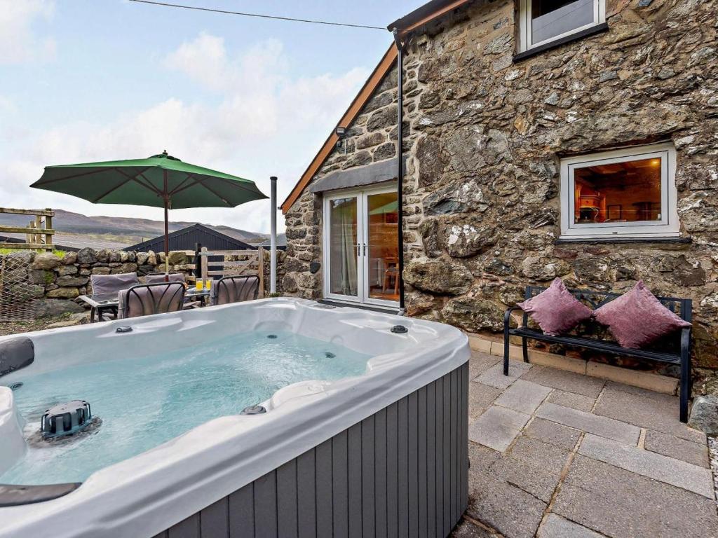 a hot tub in front of a stone house at 3 Bed in Bala oc-52810 in Llanuwchllyn