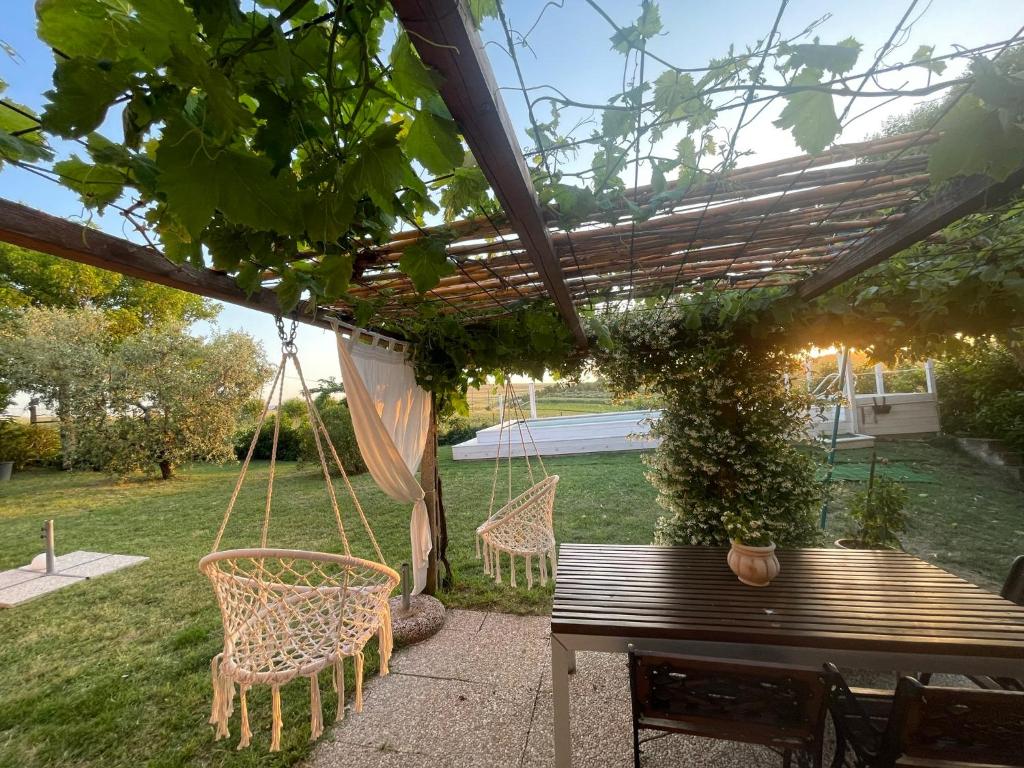 a swing under a pergola with a table and chairs at AGRITURISMO LA MOROLLA in Marsciano