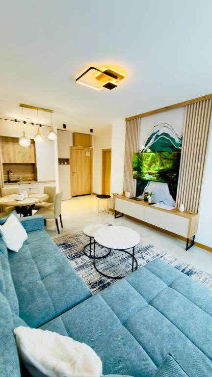 a living room with a blue couch and a fish tank at Apartman Romanija Wellness & Spa in Potoci