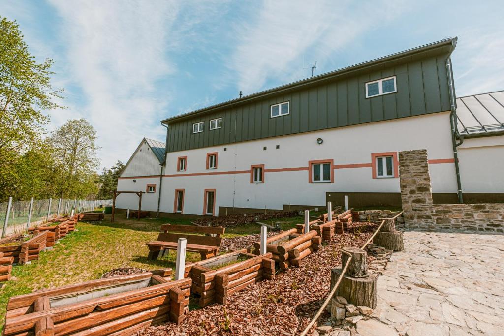 a large white building with wooden benches in front of it at U Bernarda in Slavíkovice