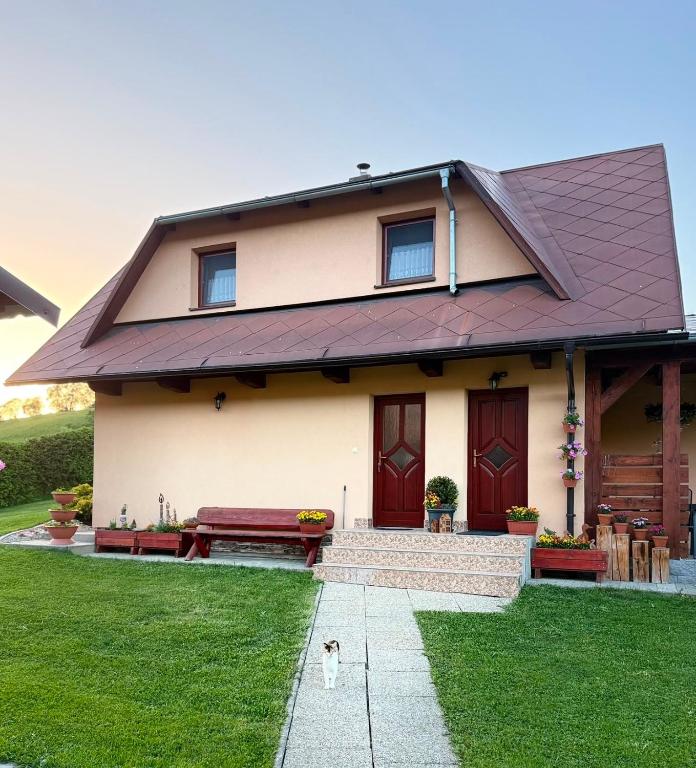 a house with a dog standing in front of it at Domček u Fera in Zázrivá