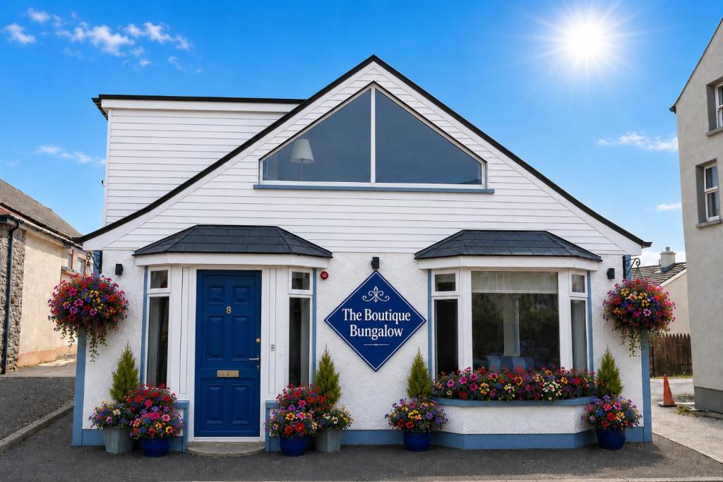 a white house with a blue door and flowers at The Boutique Bungalow in Bundoran
