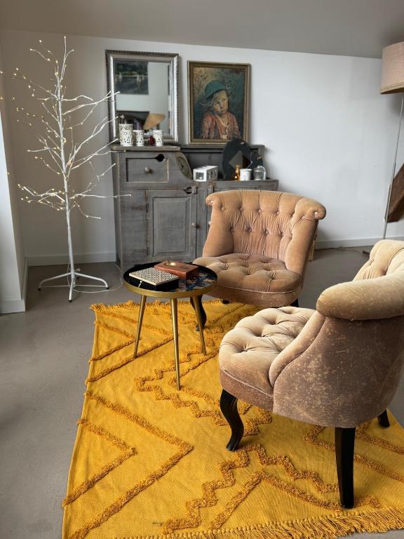 ein Wohnzimmer mit zwei Stühlen und einem Tisch in der Unterkunft Chez Arli in Attert