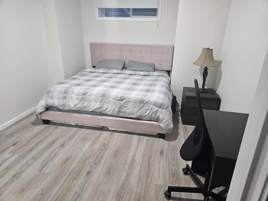 a bedroom with a bed and a desk and a television at Modern 2-Bedroom Private Basement Apartment in Airdrie