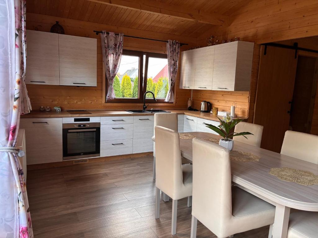 a kitchen with a table and chairs and a kitchen with white cabinets at Domek Letniskowy in Iława
