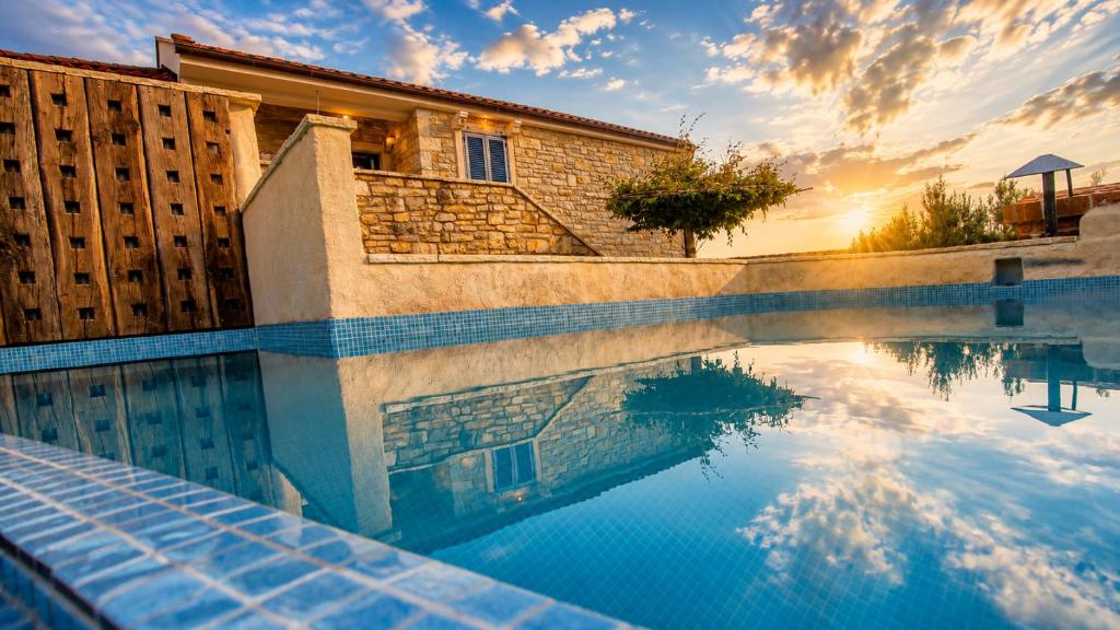 a swimming pool in front of a house with the sunset at Villa Stone Lace in Kolan