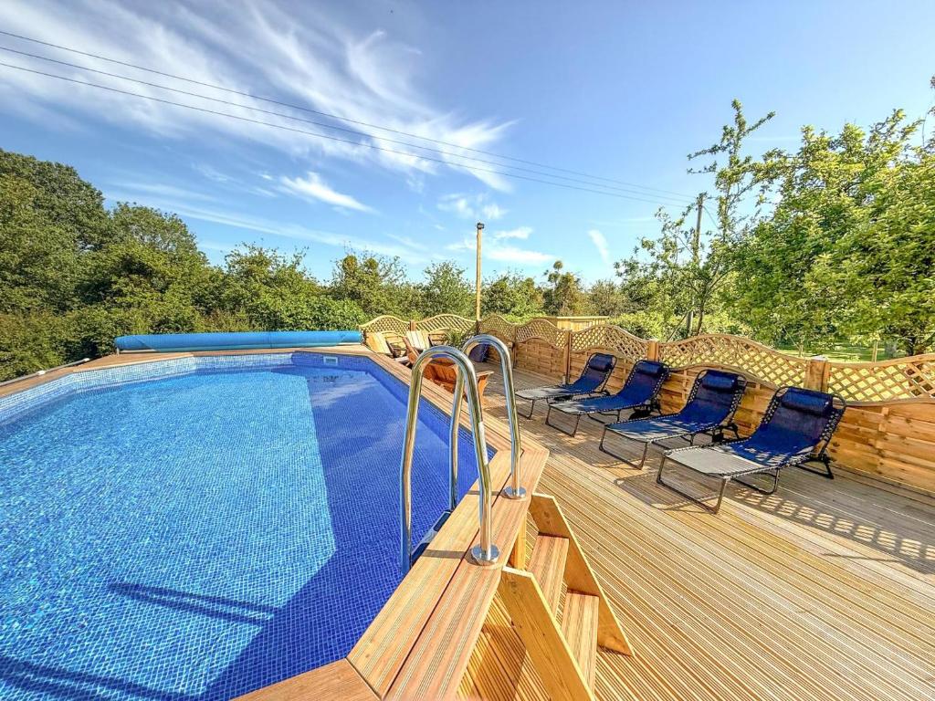 a swimming pool on a wooden deck with blue chairs at 4 Bed in Burrowbridge oc-o33020 in Athelney