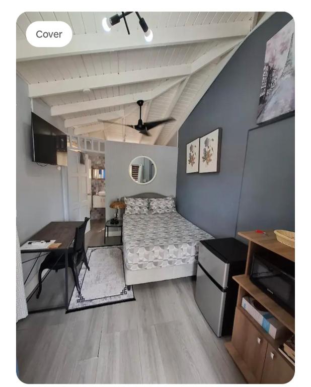 a bedroom with a bed and a desk and a table at Carmen's Cozy Studio in Bridgetown