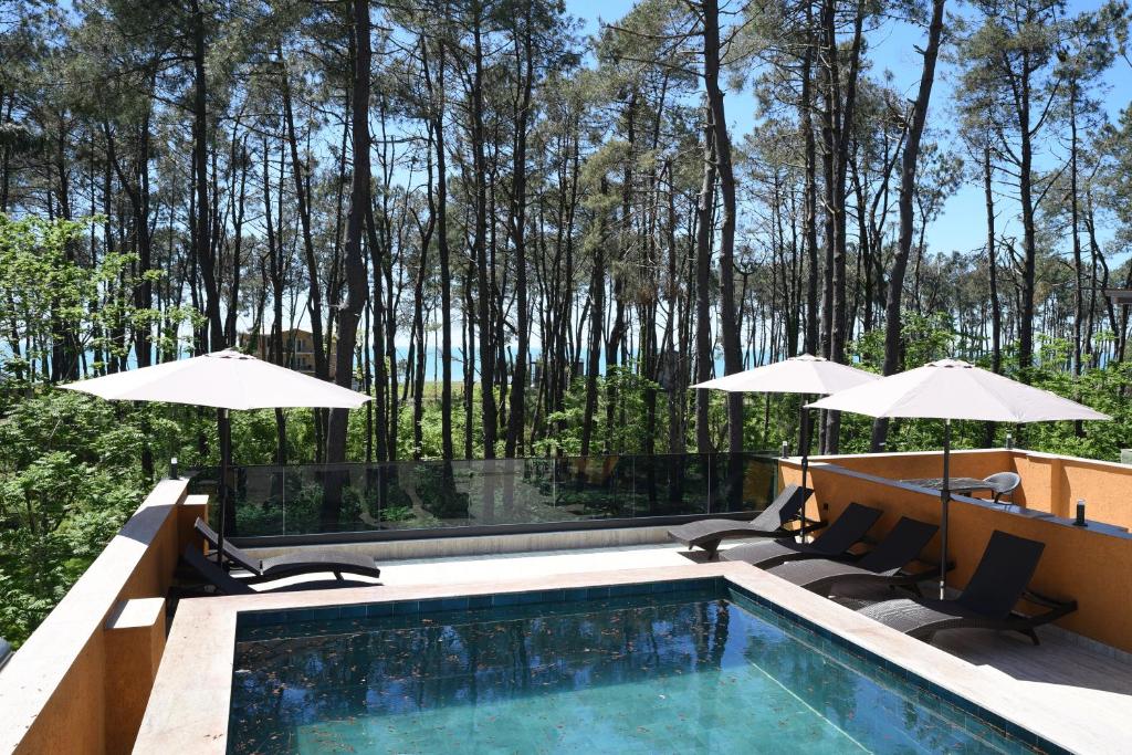 a swimming pool with two chairs and umbrellas at Bellissimo Aparthotel Aqua in Shekhvetili