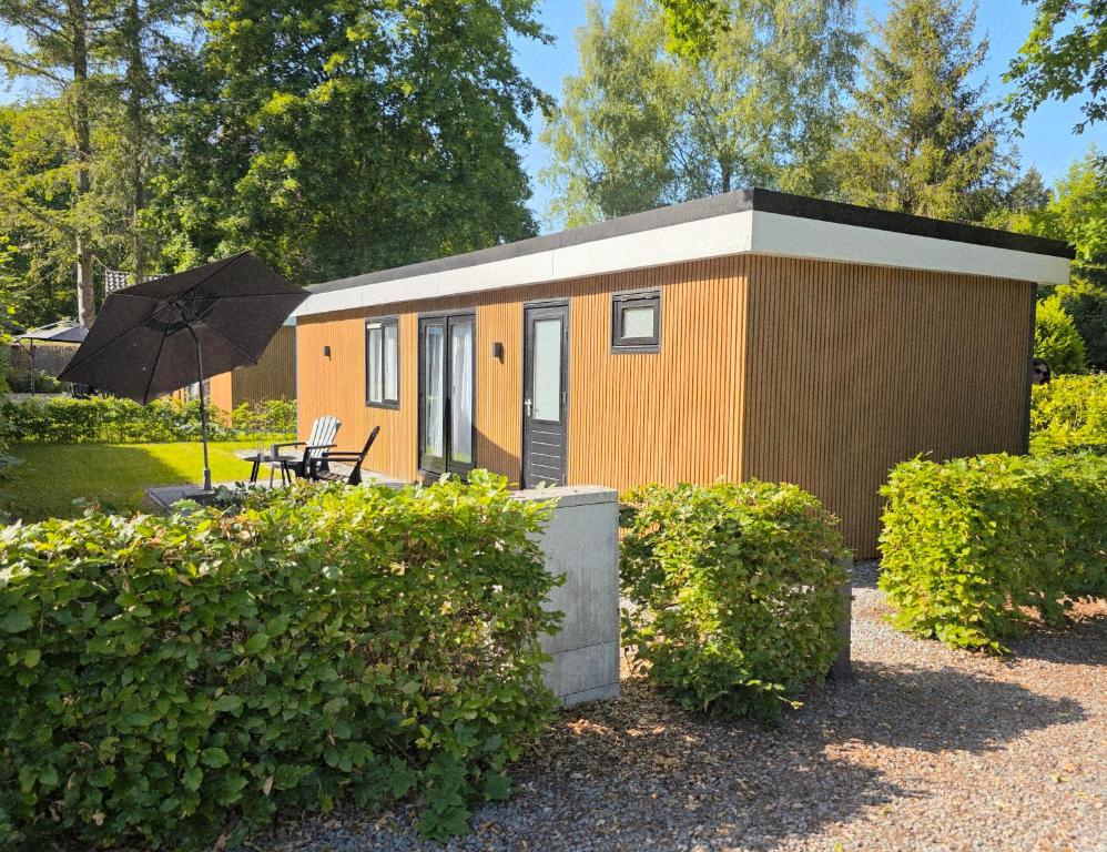 a small house with a table and an umbrella at Robin's oak lodge in Epe
