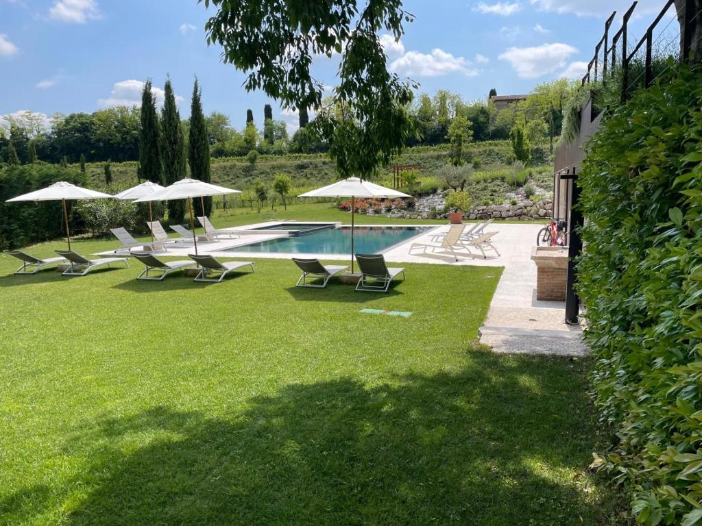 a swimming pool with lounge chairs and umbrellas at Relais Ca' Morenica in Valeggio sul Mincio