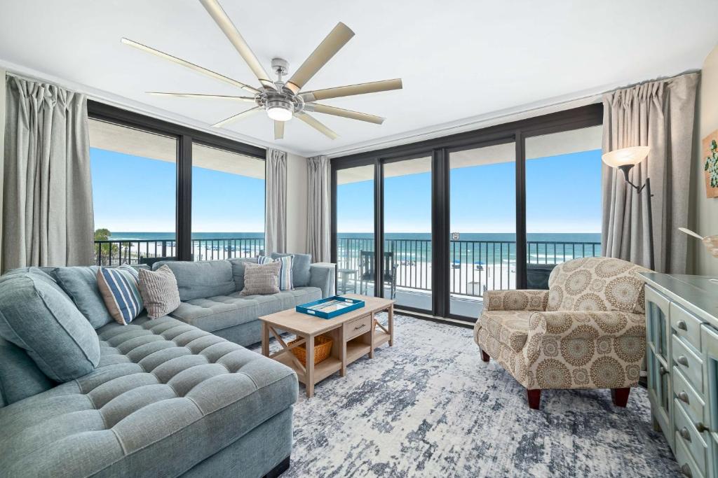 a living room with a couch and chairs and large windows at Lei Lani Unit 201T in Orange Beach