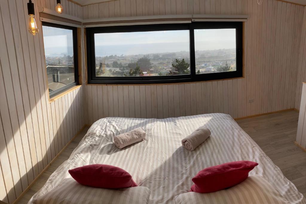 a bedroom with a bed with two pillows and a window at Tiny House con Vista al Mar, ideal para Teletrabajo o Descanso en Pichilemu in Pichilemu