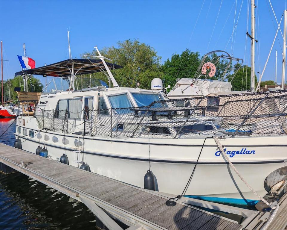 a white boat is docked at a dock at bateau nuit insolite in Carentan