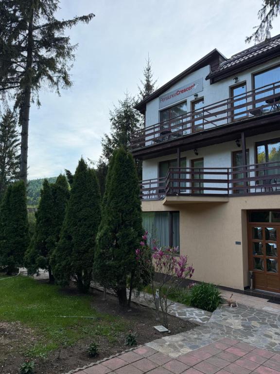 a large building with a balcony and trees at Pensiunea Crescent Predeal in Predeal