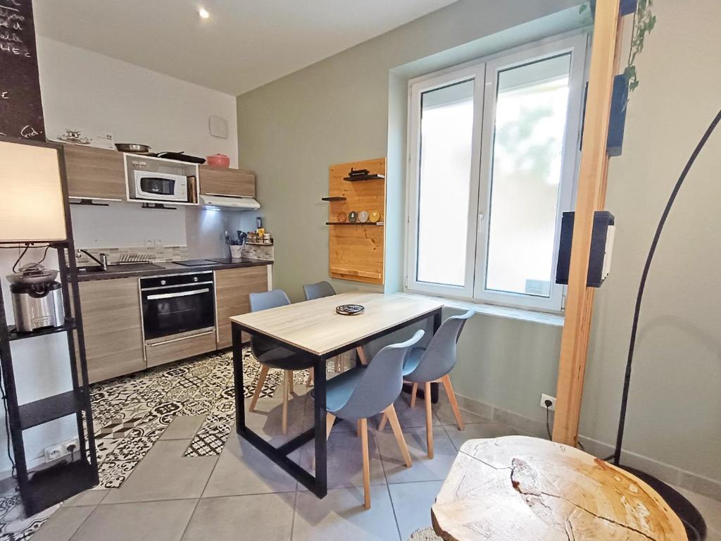 a kitchen with a table and chairs in a room at La coulée verte - superbe duplex climatisé - jardin - classé 3 étoiles in Luchon