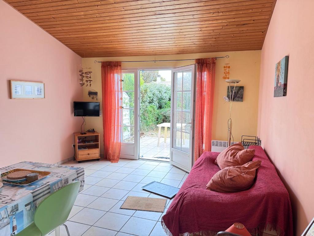 a bedroom with a bed and a sliding glass door at La petite Lotie in Saint-Denis-dʼOléron