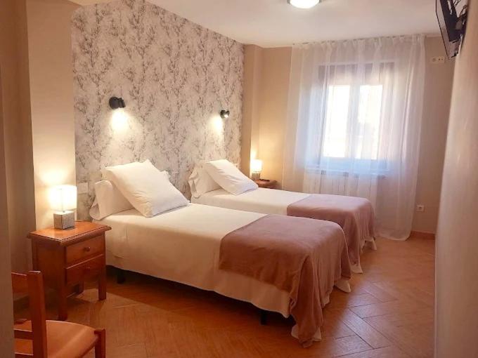 a bedroom with two beds and a window at HOTEL RURAL ORQUIDEA in Velilla del Río Carrión