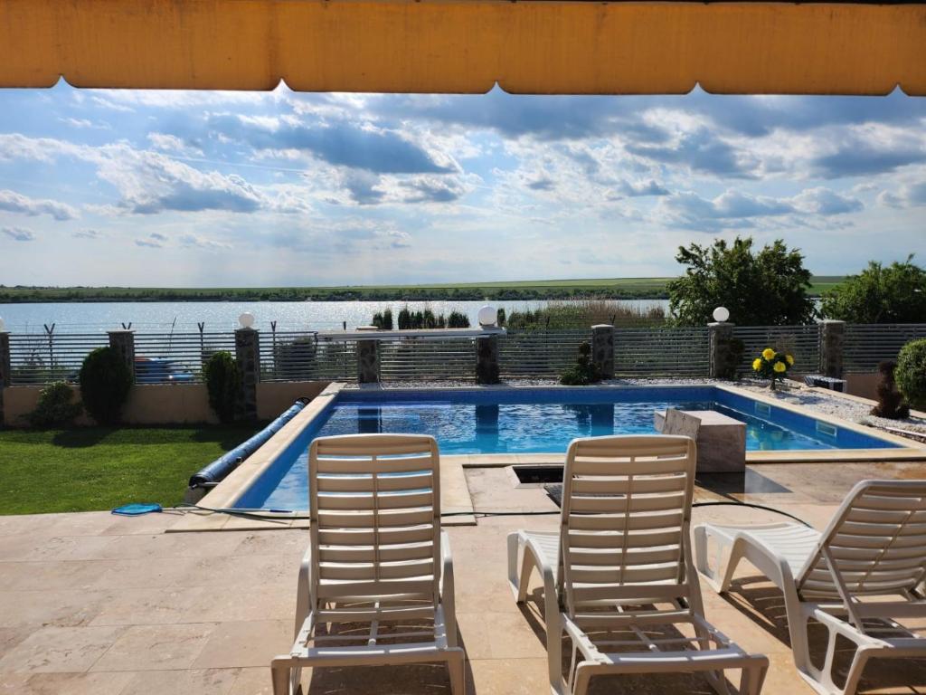 ein Schwimmbecken mit Liegestühlen und Blick aufs Wasser in der Unterkunft CasaMari in Corbu