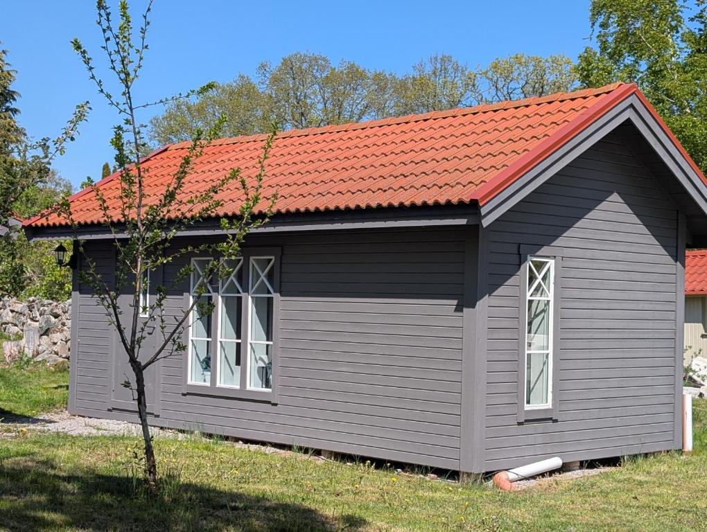 a small grey shed with an orange roof at Kuggeboda in Listerby