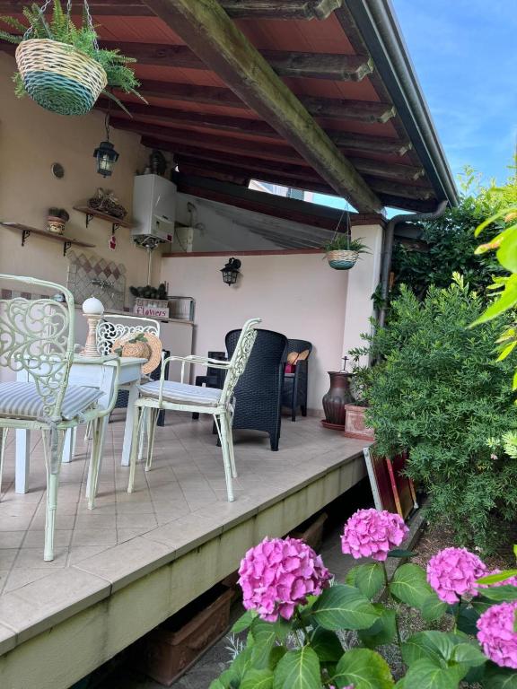 a patio with chairs and a table and some flowers at CasaEma in Torre del Lago Puccini