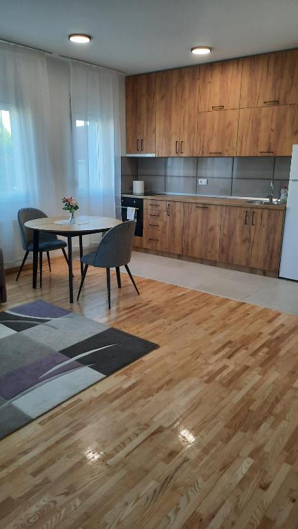 a room with a table and a kitchen with wooden cabinets at Apartman Sanja Ledine in Ledine