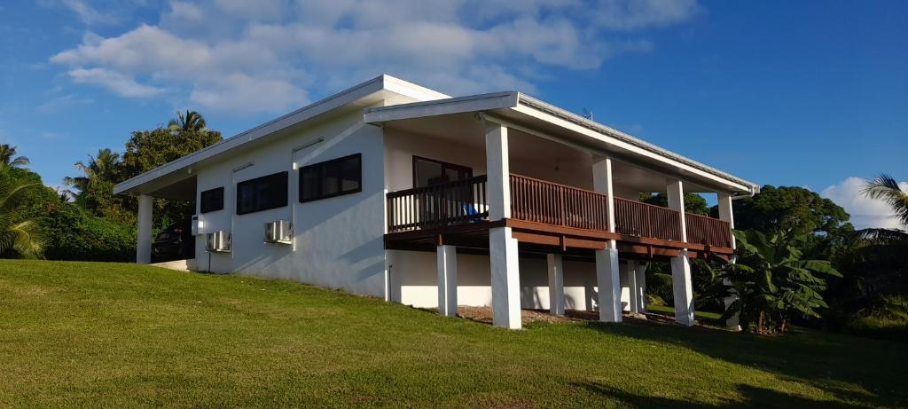 a white house with a balcony on a hill at Reureu Ocean Vistas in Arutanga