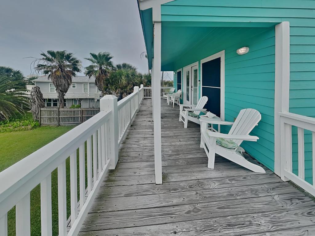 a blue house with white chairs on a porch at Sundancers in Galveston