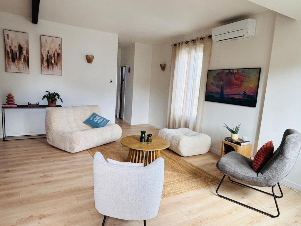 a living room with a couch and a table and chairs at Copacabane in Gujan-Mestras