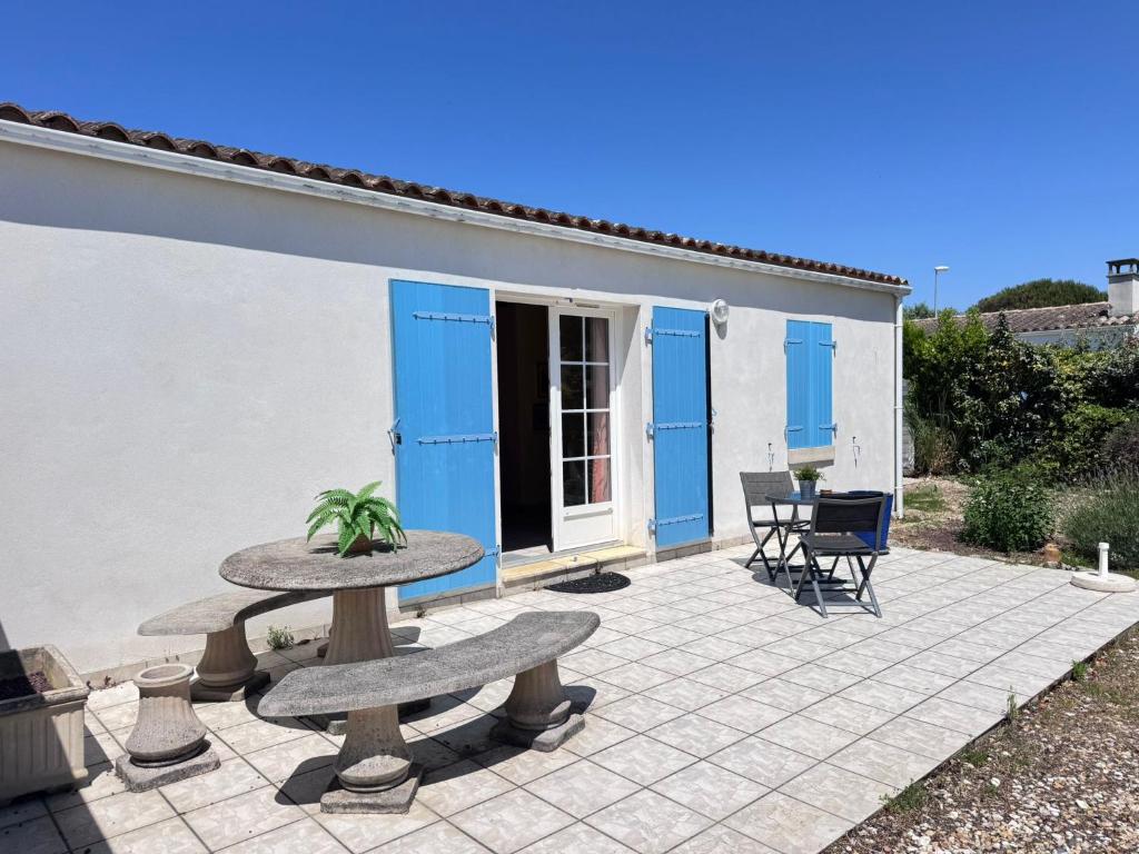 a patio with two benches and a house with blue doors at La Pierre Lotie in Saint-Denis-dʼOléron