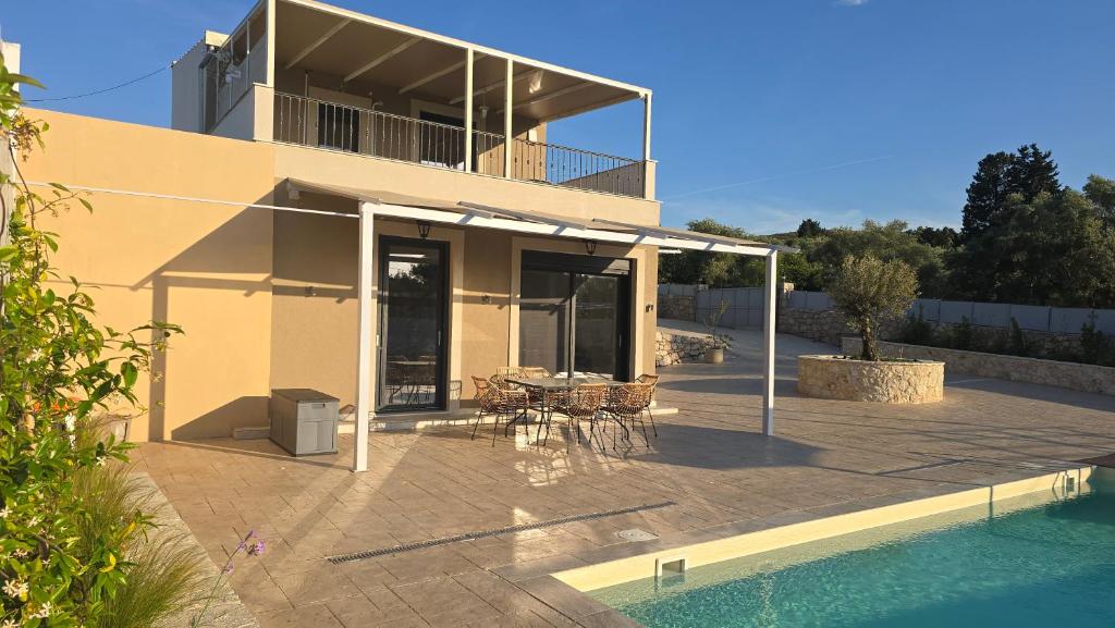 a house with a patio with a table and a pool at Villa RELAX in Tsoukalades