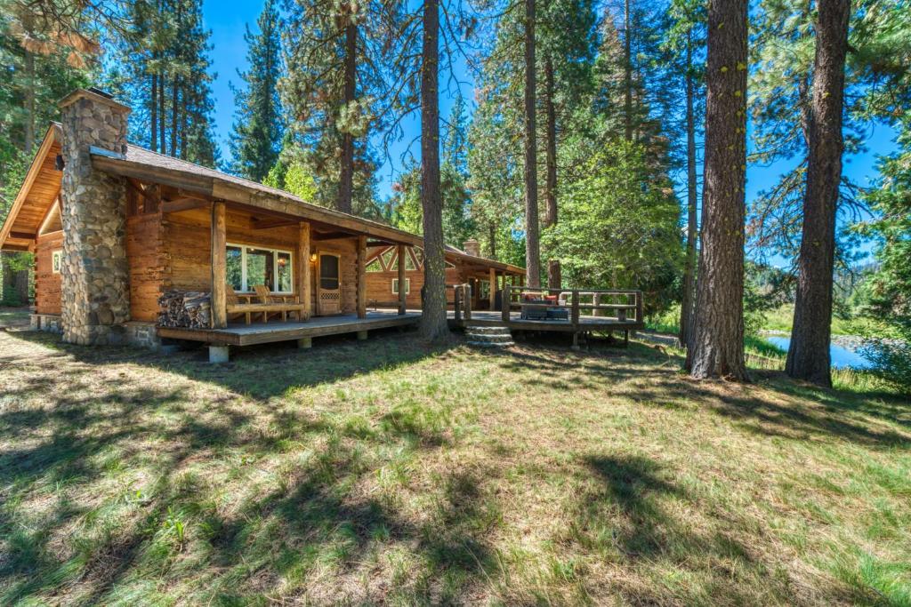 a log cabin in the woods with a picnic table at 2 Riverfront Cabins, 200 Acres Near Plumas Forest in Sloat