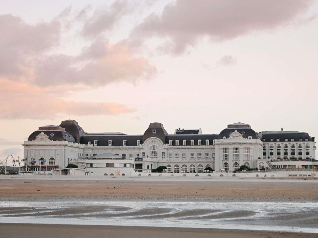 a large white building sitting on top of a beach at Cures Marines Hotel Thalasso & Spa Trouville - MGallery Collection in Trouville-sur-Mer