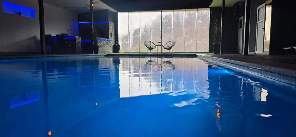 a swimming pool with blue water in a building at Vikendica Tuzla baracuda bazen in Slavinovići