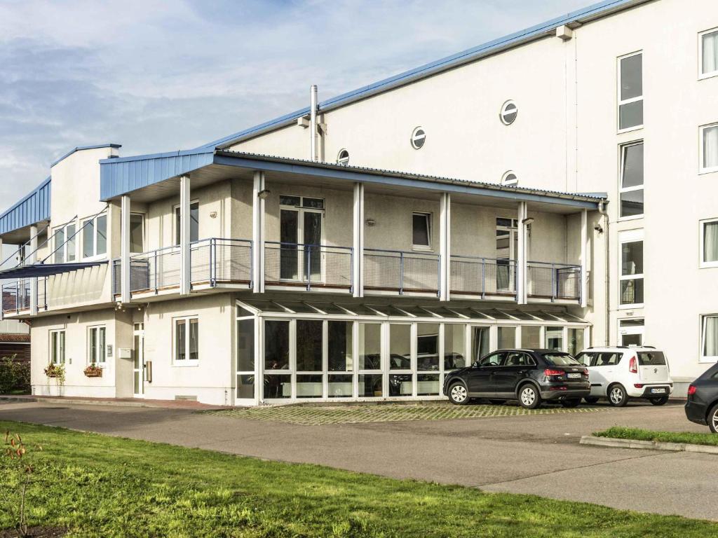 a white building with cars parked in front of it at ibis Leipzig Nord-Ost in Leipzig