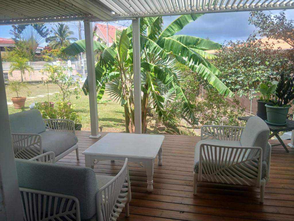 a patio with a white table and chairs on a deck at Maison créole chaleureuse - Centre Sud Martinique in Ducos
