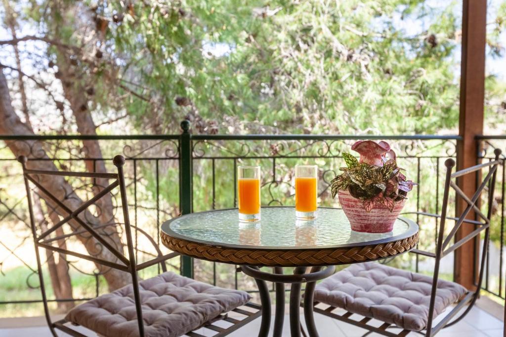 a table with two glasses of orange juice on a balcony at Thimeli Hotel in Lygourio