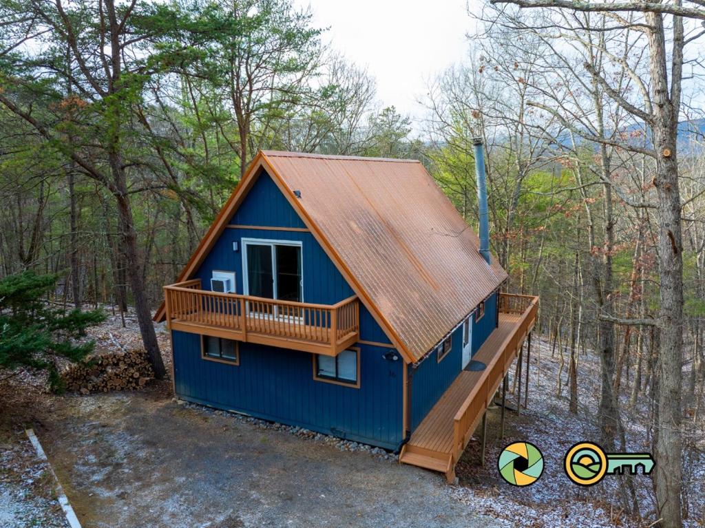 a blue cabin with a deck in the woods at 16 Deloris Road: Coppertop Chalet in Basye