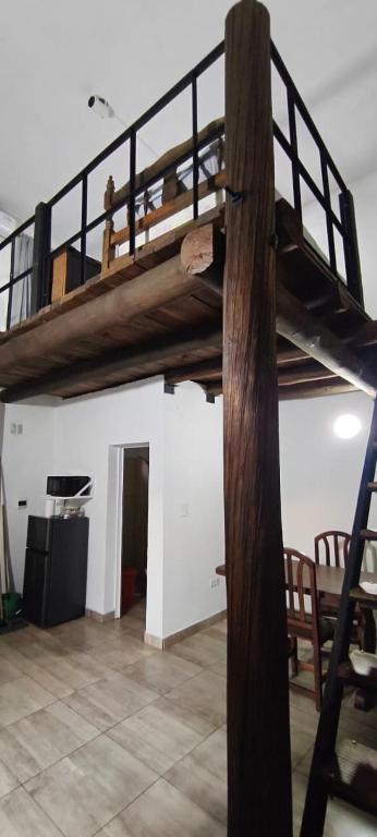 a loft bed in a room with a wooden ladder at El Refugio - Departamentos in Metán Viejo