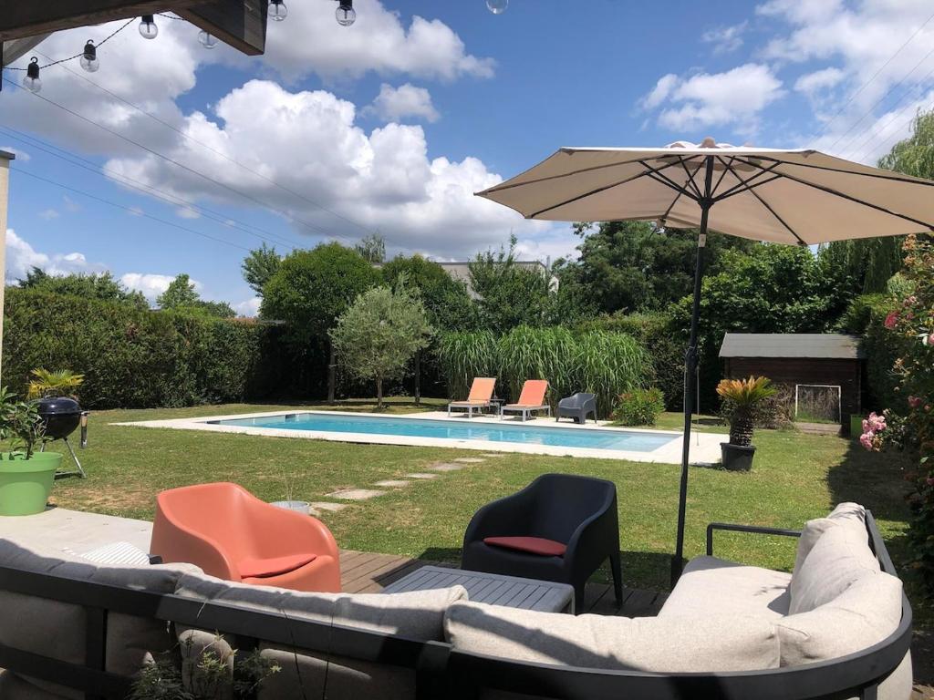 a patio with chairs and an umbrella next to a pool at Single-storey house in Saint-Cyr in Saint-Cyr-sur-Loire