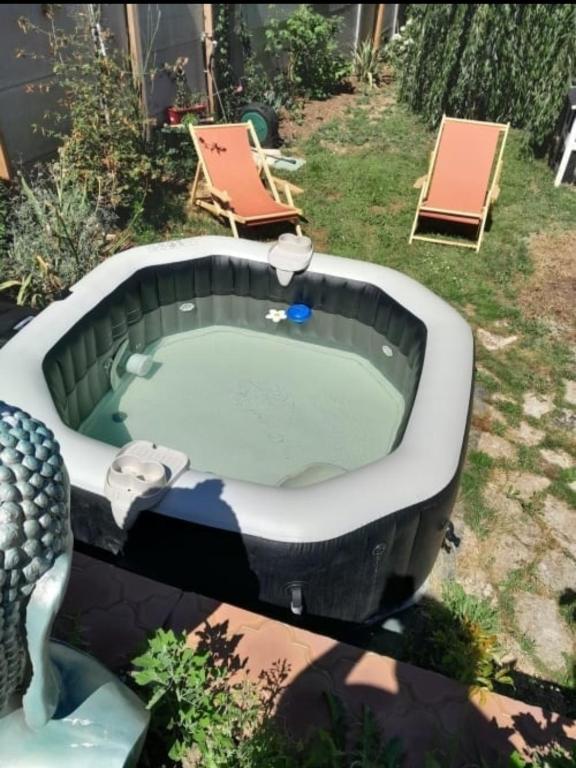 a bath tub in a yard with two chairs at Chambre calme avec vue sur le jardin, idéale pour une pause nature proche du centre de Chartres in Chartres
