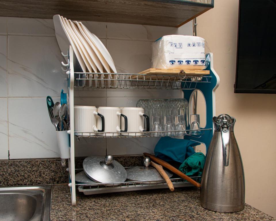 a kitchen counter with a shelf with dishes and utensils at Delore suits in Ongata Rongai 