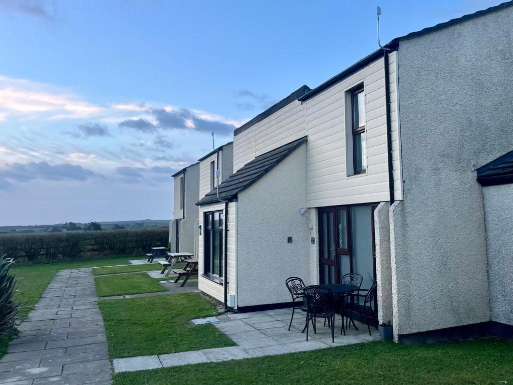 a building with a patio with tables and chairs at 39 Perran View Your Home Away from Home in Cornwall in St. Agnes