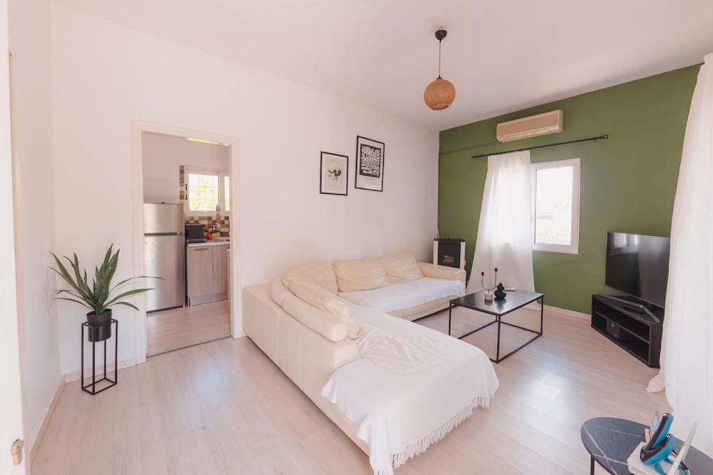a living room with a white couch and a television at Zoumperi Summer House in Nea Makri